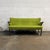 A vintage Danish sofa dating to the early 1950s, with a sculptural winged back, slender teak arm caps, and gently splayed...