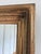 An antique French giltwood wall mirror, dating to the late 19th century. This rectangular mirror has a warm gold frame...