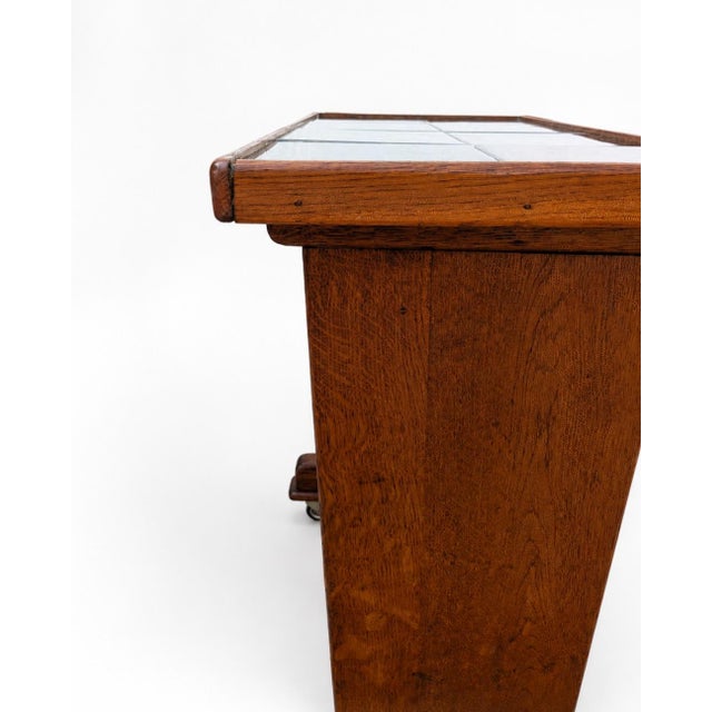 Side or serving table in stained oak with a black tile top and wheels. Mid-century utilitarian design from the 1950s. In...