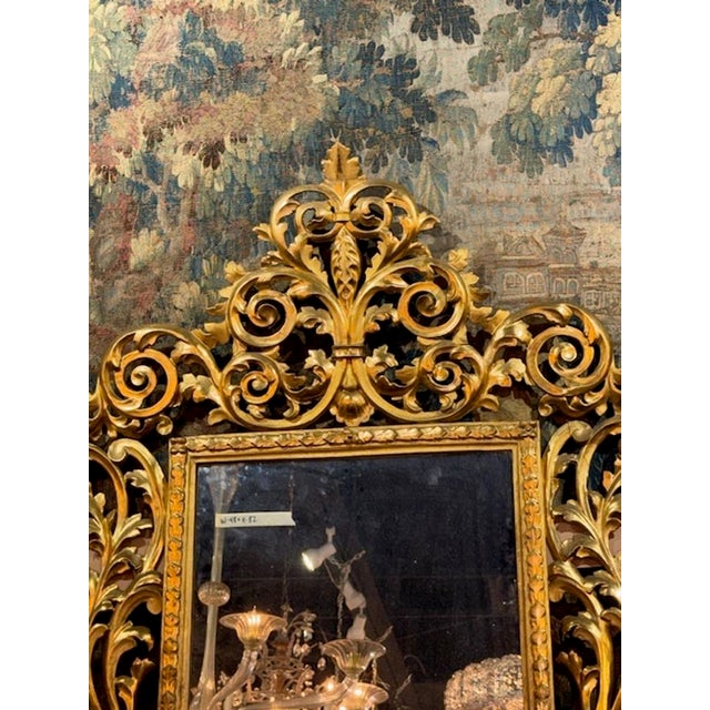 The 19th Century Italian Florentine Carved and Giltwood Mirror exudes opulence with intricate carvings and giltwood...