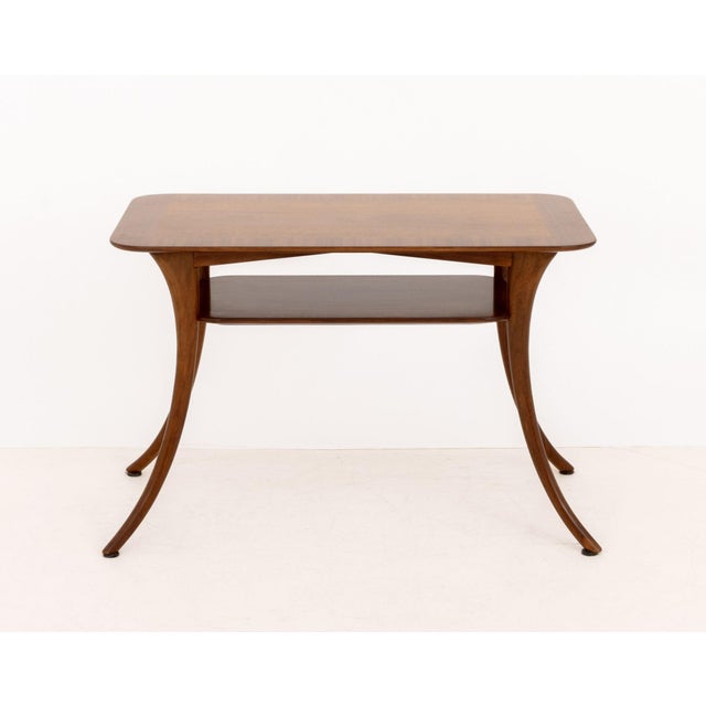 T. H. Robsjohn-Gibbings (British, 1903-1976) for Widdicomb Walnut Table, with two-tiers above saber legs, label to...