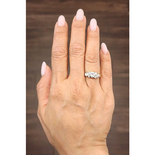 A stunning natural 1.07-carat round diamond takes center stage, exhibiting its pristine white hue. Flanked by...