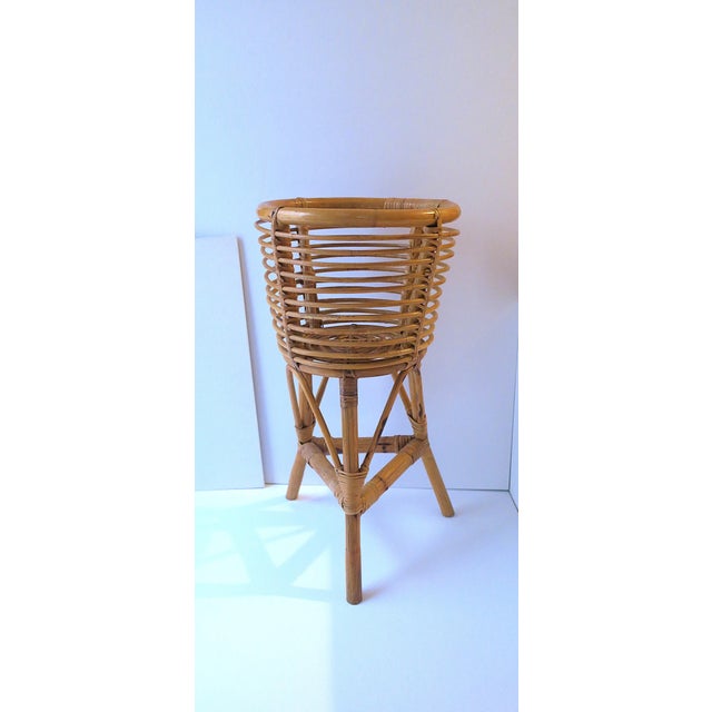 A natural wicker wrapped rattan plant potholder cachepot stand with tri-pod base, circa late-20th century. Hold a plant or...