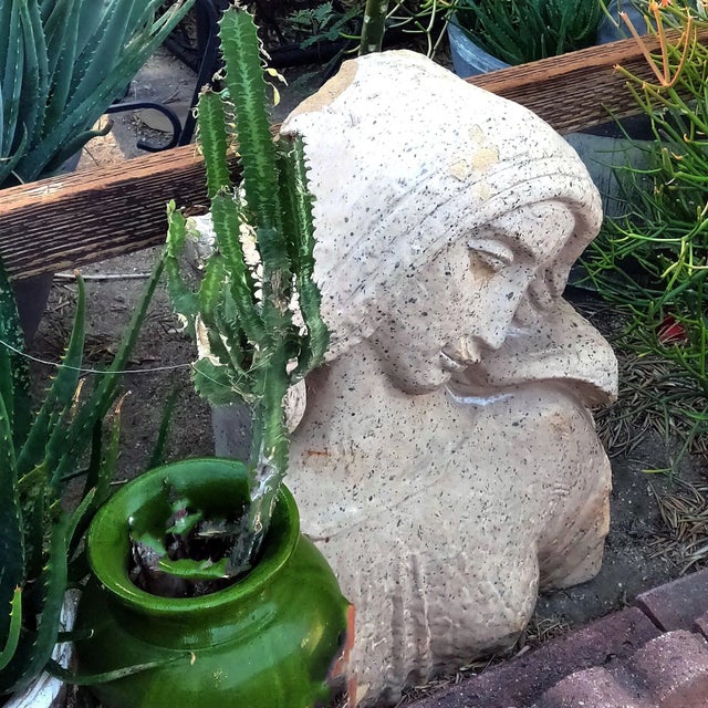 An unusual and likely one of a kind cast bas relief cement bust of a shy maiden depicted in a demure pose with tilted...