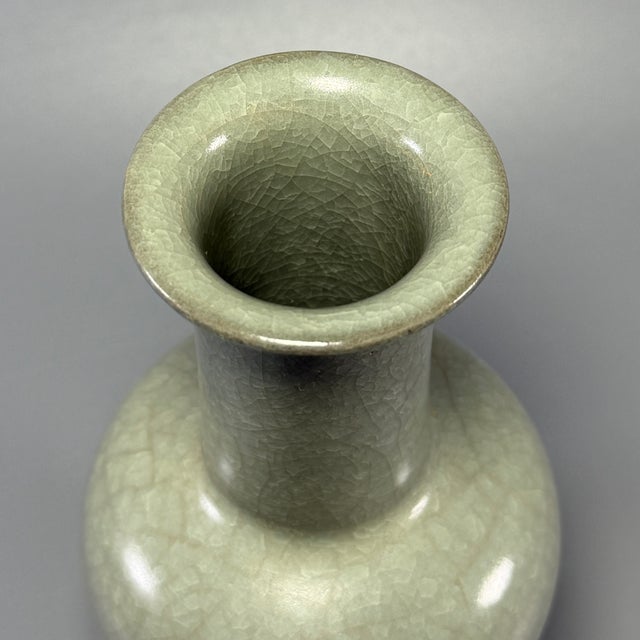 Elegant Chinese celadon porcelain long‑neck vase with a graceful flared rim and well‑proportioned full body. It is...