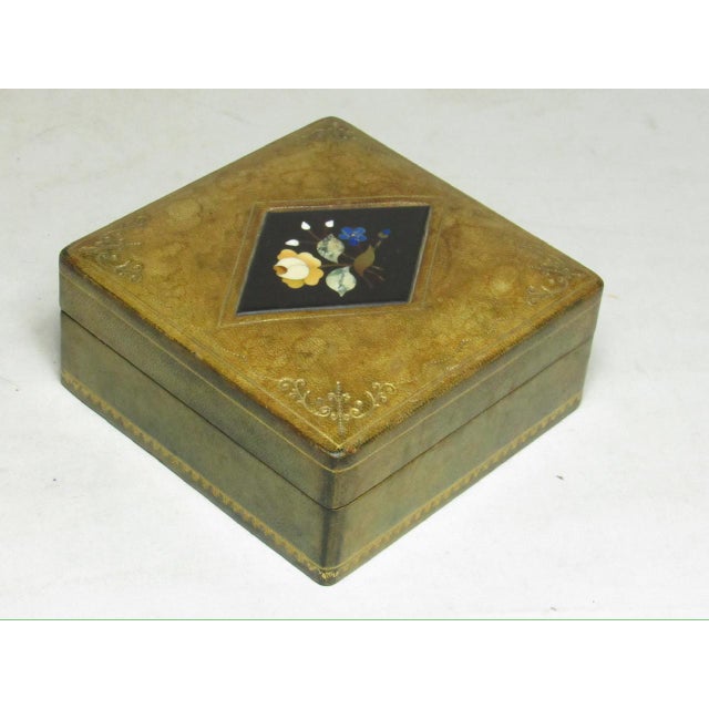 Italian tooled and gilded square leather box inset with a diamond shaped inlaid Pietra Dura panel. The pale green leather...