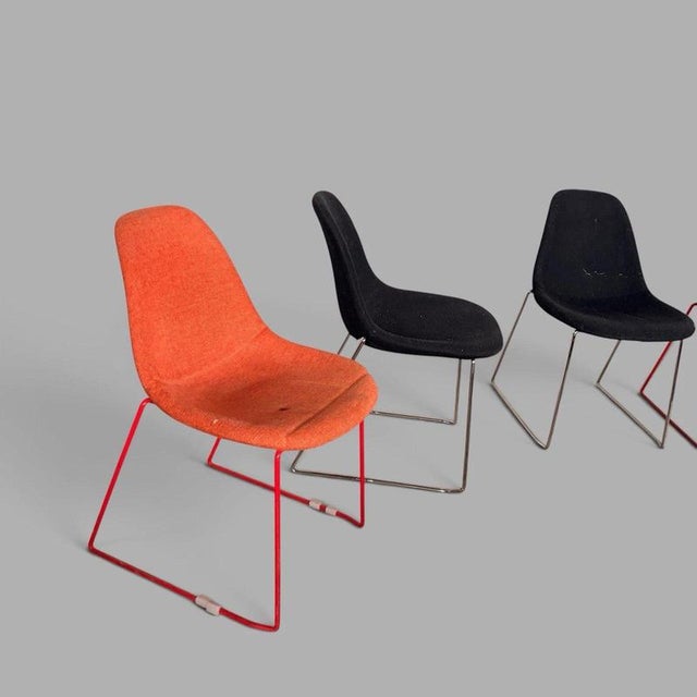 a striking set of four mid-century stackable egg dining chairs upholstered in contrasting orange and black fabric. Their...