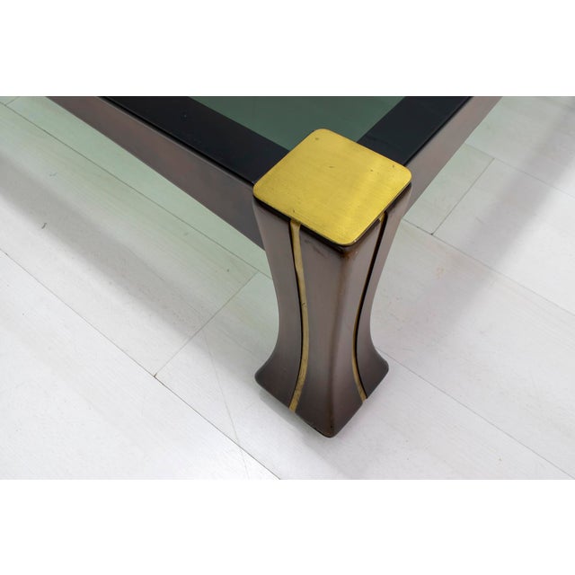 This coffee table is made of walnut with brass trim and a smoked glass top. This model is part of the "Ussaro" collection...