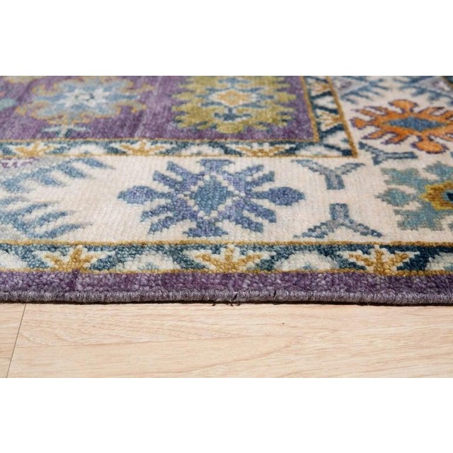 This hand knotted pile rug features a primary color palette of purple, lavender, and mauve. Crafted from genuine wool,...