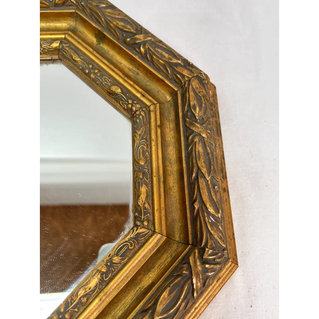 Gilt frame with borders decorated in leaves, ribbons and florals. Has a deep cove between the borders. Glass has good...