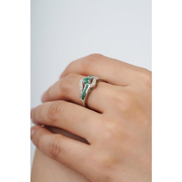Crafted in 925 sterling silver, this contemporary ring showcases vibrant emeralds totaling 0.87 carats, accented by...