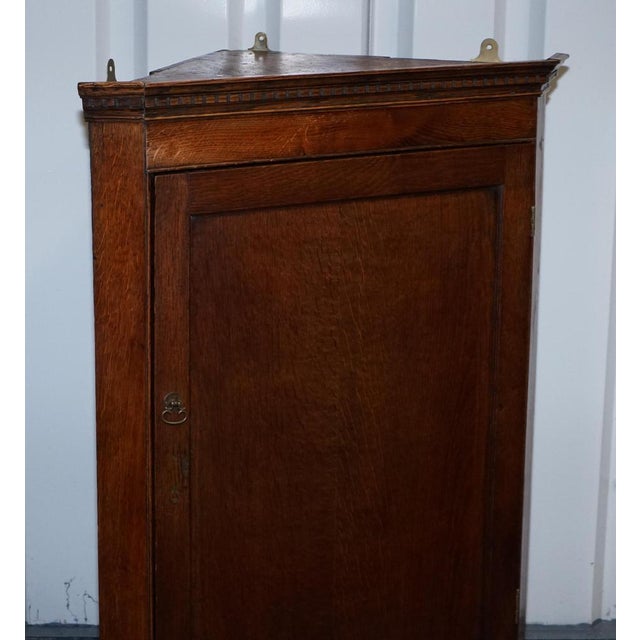 This charming antique English corner cupboard is crafted from solid oak and designed to hang neatly into the corner of a...