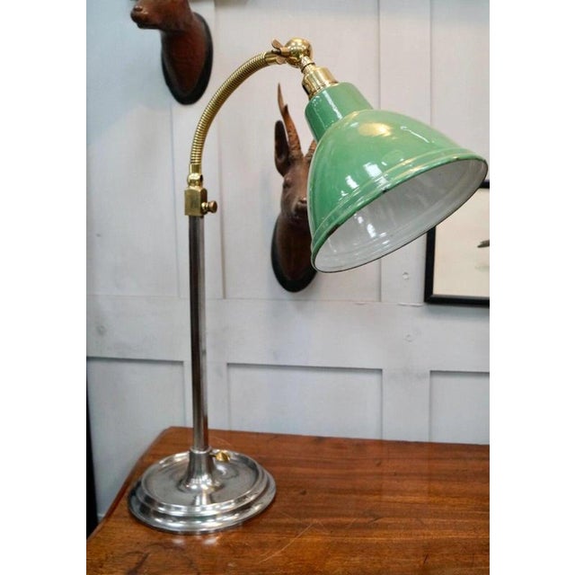 A charming antique reading lamp dating to circa 1920, combining a patinated brass gooseneck with its original green enamel...