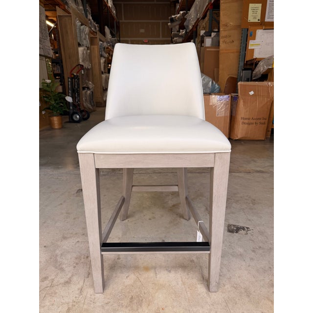 Contemporary counter stool featuring a clean, tailored silhouette upholstered in smooth light gray leather for a refined,...