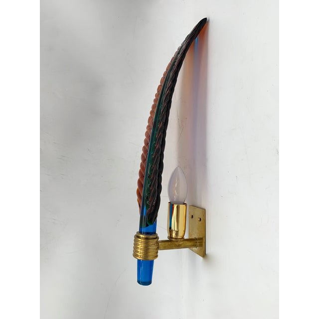 The lamp features an elongated, vertical shape reminiscent of a stylized leaf. Crafted from glass with engraved, wavy...