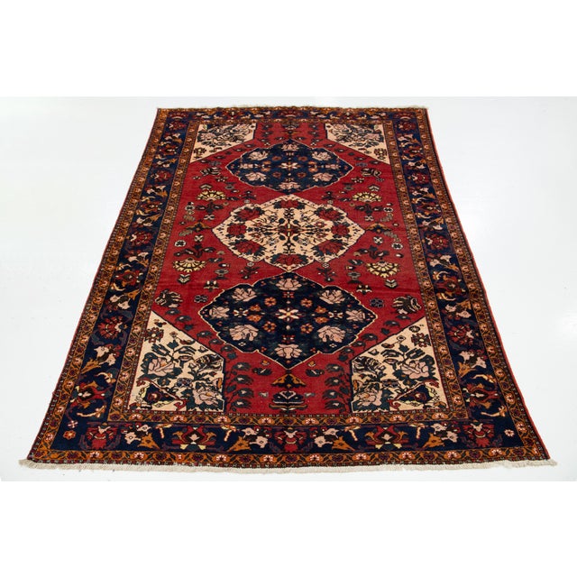 This handcrafted Persian Shiraz wool rug features a vibrant red field adorned with multicolored accents throughout the...