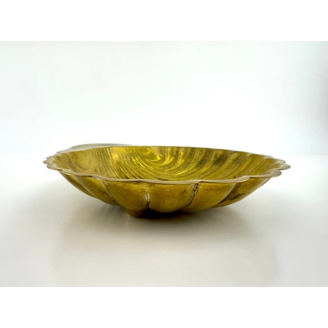 Antique French pressed brass shell dish, elegantly formed with deep fluting and a scalloped edge, dating to circa 1900....