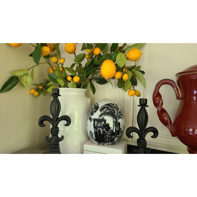 An all-white ceramic egg is the backdrop for a coastal city/architectural scene in black silhouette with seagulls...