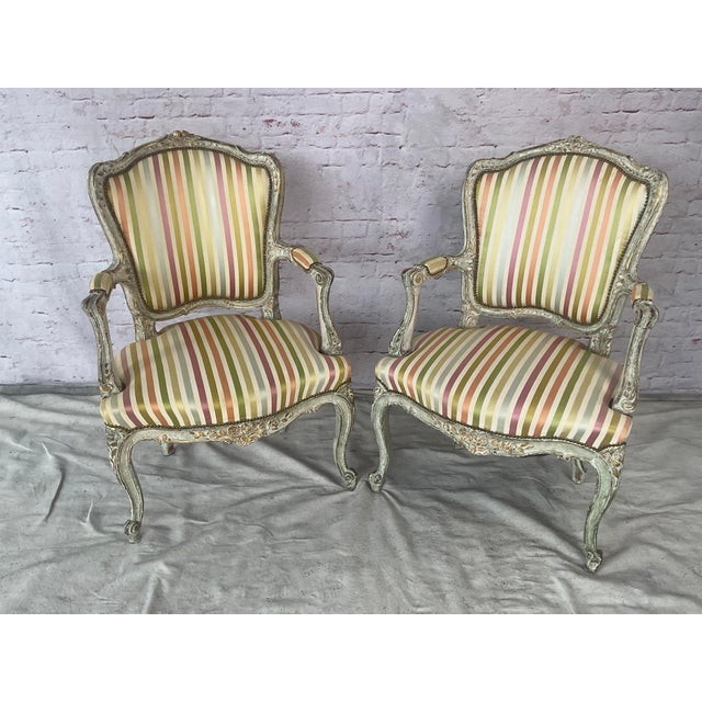 Pair of French Louis XV Style Fauteuil Armchairs. Armchairs are hand-crafted with flowing Rococo lines, and feature a...