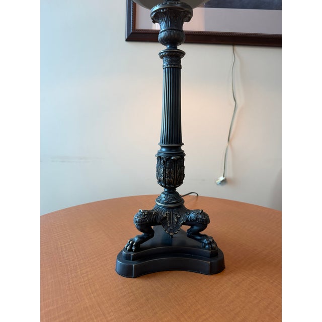 A Haig dual-light table lamp crafted from solid brass with a bronze finish. The lamp features a classical column with...