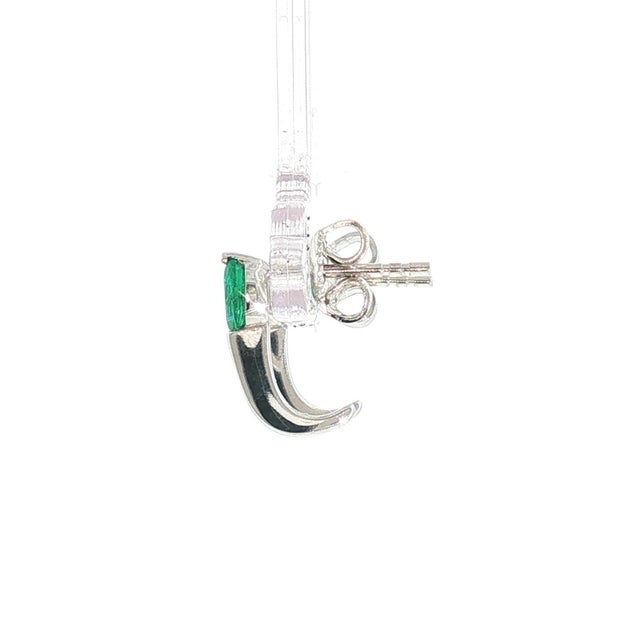 A pair of contemporary white gold J hoop earrings featuring oval-cut green emeralds. Each earring is adorned with a...