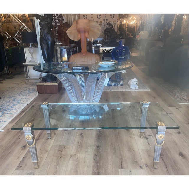 An elegant Louis XVI style coffee table by P.E. Guerin, featuring a rectangular glass top supported by four finely cast...