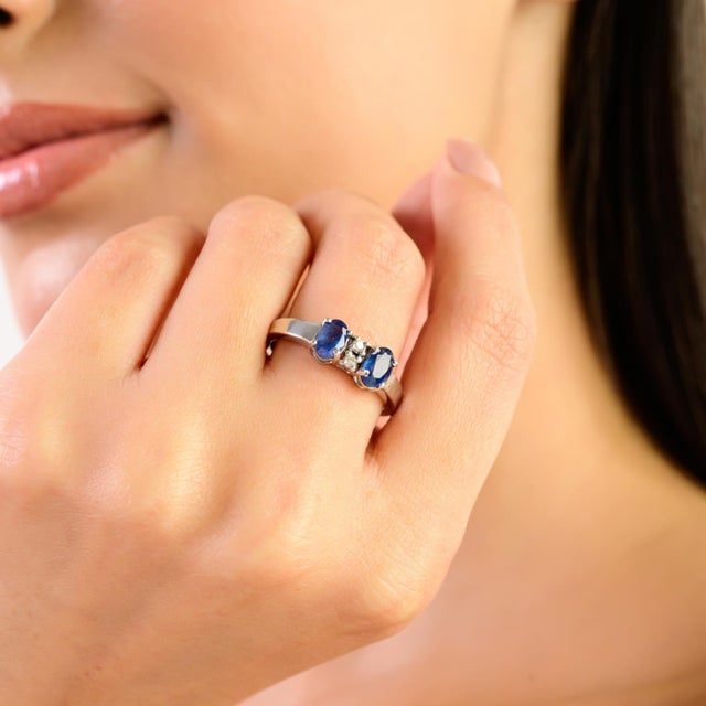 This elegant women’s ring is crafted in 925 silver and features two blue sapphire gemstones in a classic oval and round...