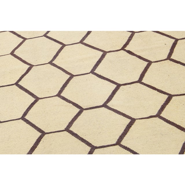 This contemporary Kilim rug has been expertly hand-knotted with a captivating beige field design complemented by subtle...