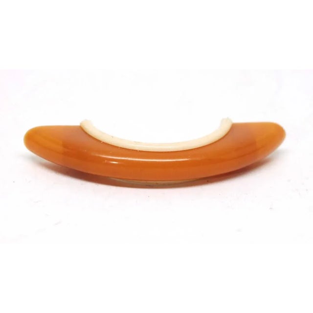 Orange bridge drawer pull with an off white edging along the back and sides of the handle. Good condition with appropriate...