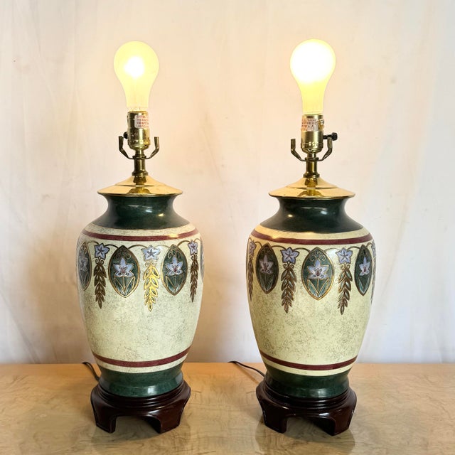 This elegant pair of hand-painted table lamps features rich green, gold, and cream tones with ornate floral motifs and...