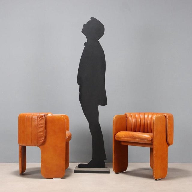 A pair of armchairs with cognac-colored leather upholstery. They show some signs of wear, as shown in the photographs....