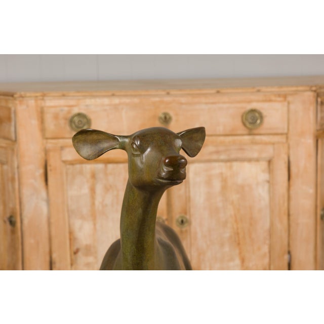 A Continental life size bronze sculpture depicting a deer, circa 1930. Elevate your outdoor space with the captivating...