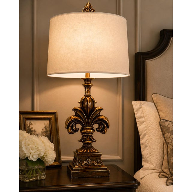 PAIR OF FRENCH PROVINCIAL GILDED FLEUR-DE-LIS TABLE LAMPS WITH WHITE LINEN DRUM SHADES A striking pair of sculptural...
