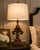 PAIR OF FRENCH PROVINCIAL GILDED FLEUR-DE-LIS TABLE LAMPS WITH WHITE LINEN DRUM SHADES A striking pair of sculptural...