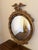 A Federal-style giltwood convex mirror crowned with a carved eagle, its wings outstretched above a laurel motif—an...