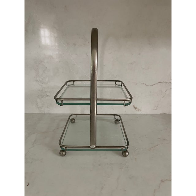 This lovely small server is ready for high tea. It’s a double tiered glass in a chrome frame with ball feet and tall...