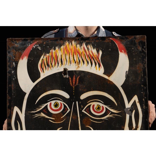 Mid-20th-century hand-painted carnival ride or haunted house wall panel depicting a dramatic drishti bommai, a protective...