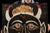 Mid-20th-century hand-painted carnival ride or haunted house wall panel depicting a dramatic drishti bommai, a protective...
