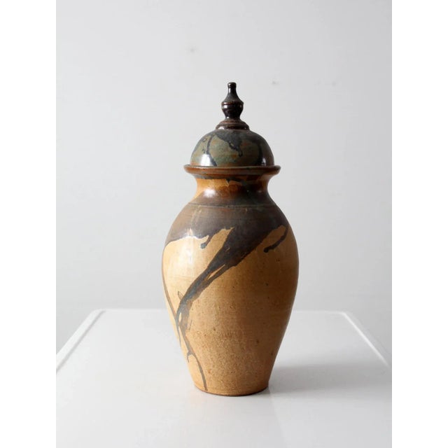 This signed vintage studio pottery vase features a dynamic, hand-crafted urn form with a bold drip glaze cascading from...