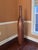 Monumental handcrafted sculptural floor vase with an elegant elongated bottle silhouette and rich warm brown finish. This...