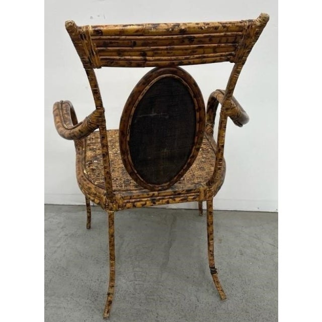 Elegant pair of Regency-style armchairs crafted of faux tortoiseshell-decorated bamboo with woven rattan seats and oval...