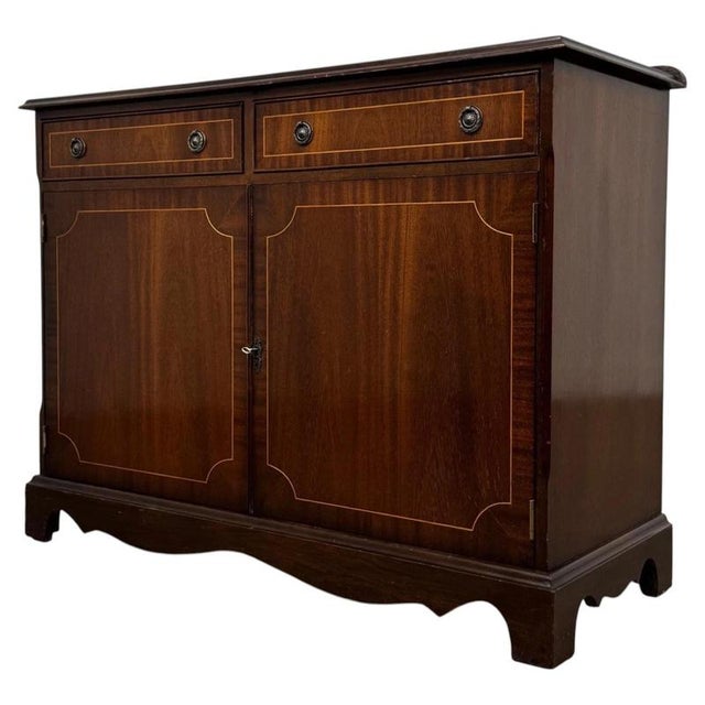 An elegant early 20th-century English cupboard, finely crafted from mahogany and distinguished by its crossbanded...