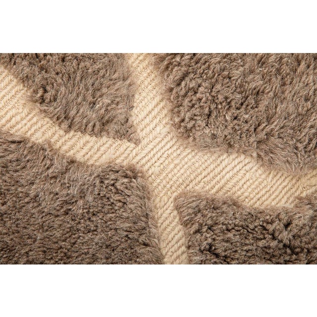 Cracks of light, running through stone. This hand-knotted Moroccan wool rug features a striking network of ivory lines...