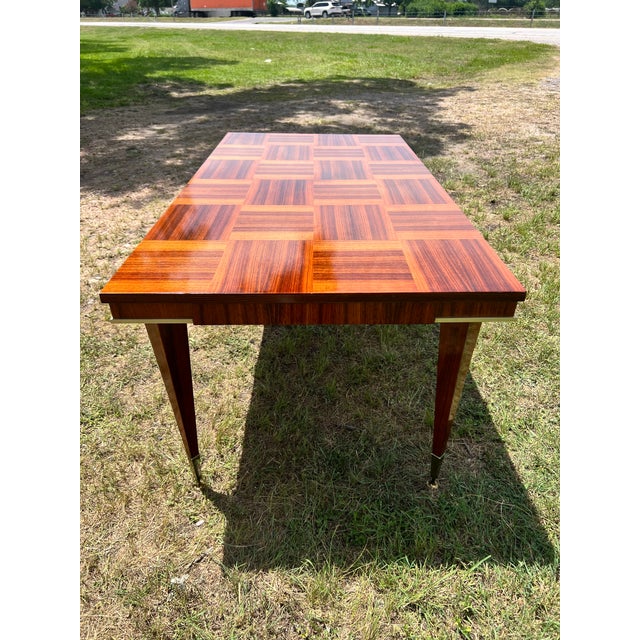 Mid-Century Modern Dining Table featuring a striking geometric parquet-style rosewood veneer top with rich, dramatic...