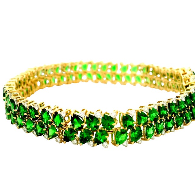 A contemporary tennis bracelet, showcasing a stunning array of pear green tsavorites, totaling 15.90 carats. The vibrant...