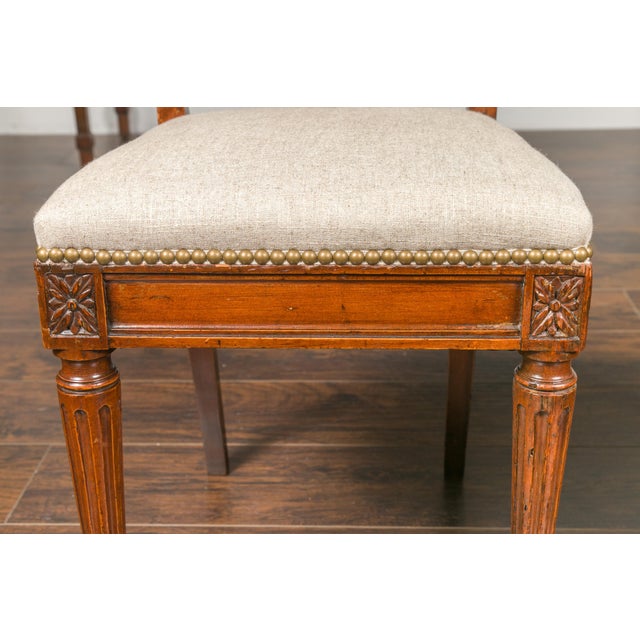 A set of four Italian neoclassical walnut dining room side chairs from the early 19th century, with carved splat, fluted...