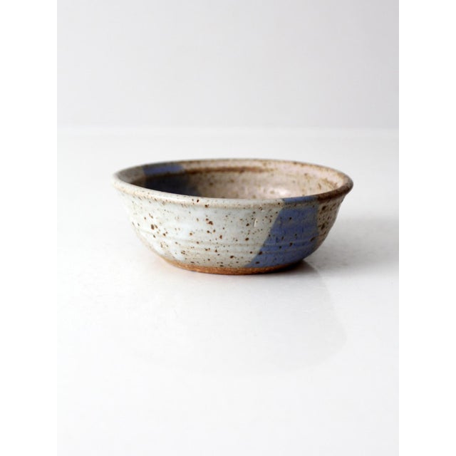Vintage handmade studio pottery bowl with a warm speckled glaze accented by a broad wash of lavender-blue. The gently...