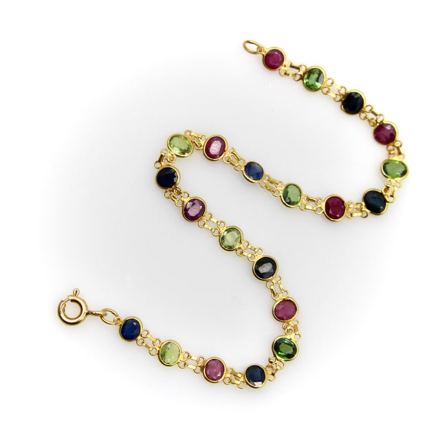 This is a handmade bracelet with oval rubies and sapphires that alternate in color between green, blue, and red. The...