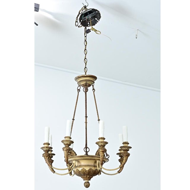A 19th-century French chandelier with carved acanthus leaf and eagle head motifs, painted to look like brass. The wood...