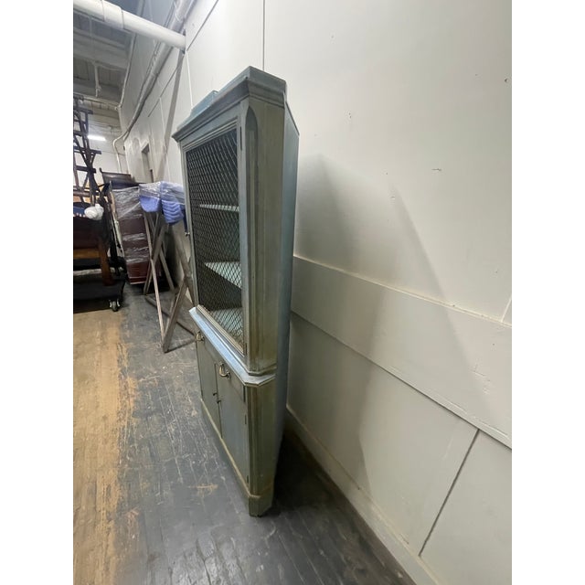 A vintage French Provincial blue painted corner cabinet with a rectangular pediment, single wire mesh hinged door, two...